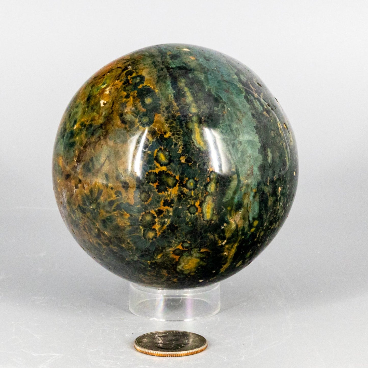 Decorative ocean jasper sphere with green and brown patterns on a white background