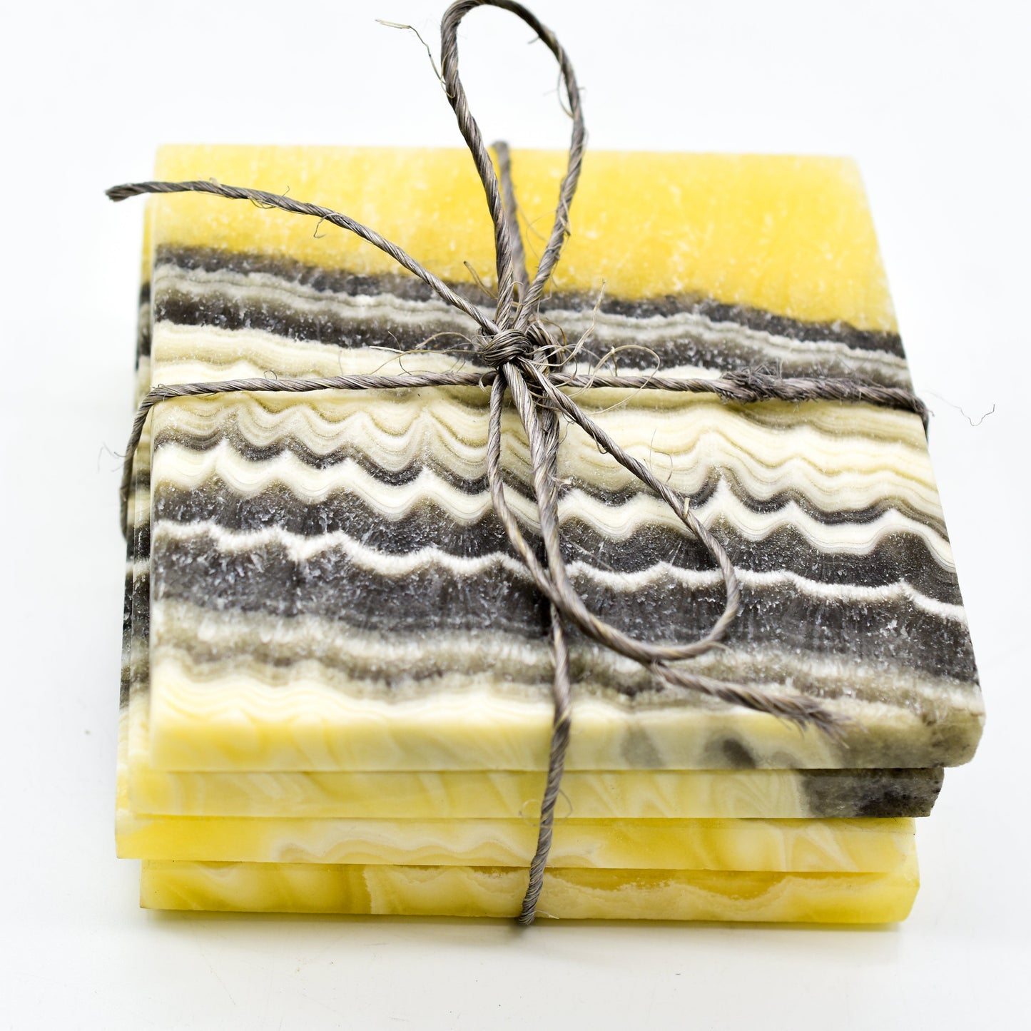 Stack of marbled yellow and gray coasters tied with twine on a white background