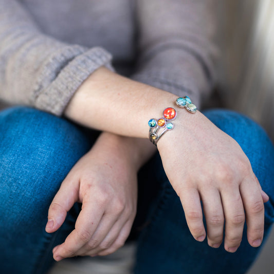 Person wearing a colorful bracelet on their wrist with a neutral background