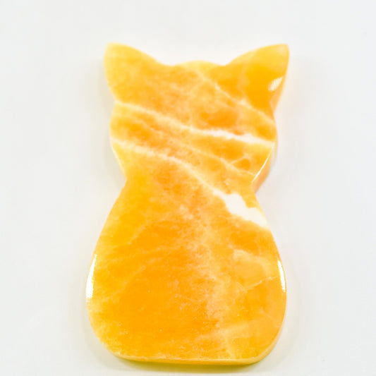 Orange cat-shaped calcite crystal on a white background