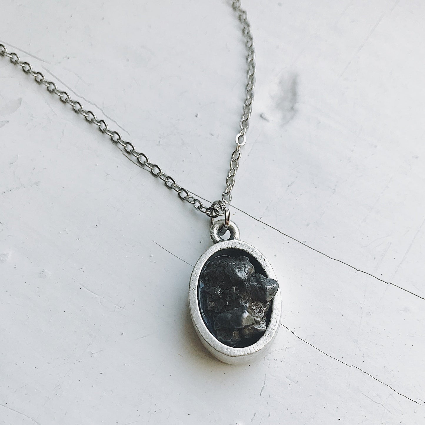 Necklace with a pendant featuring meteorite on a light gray background