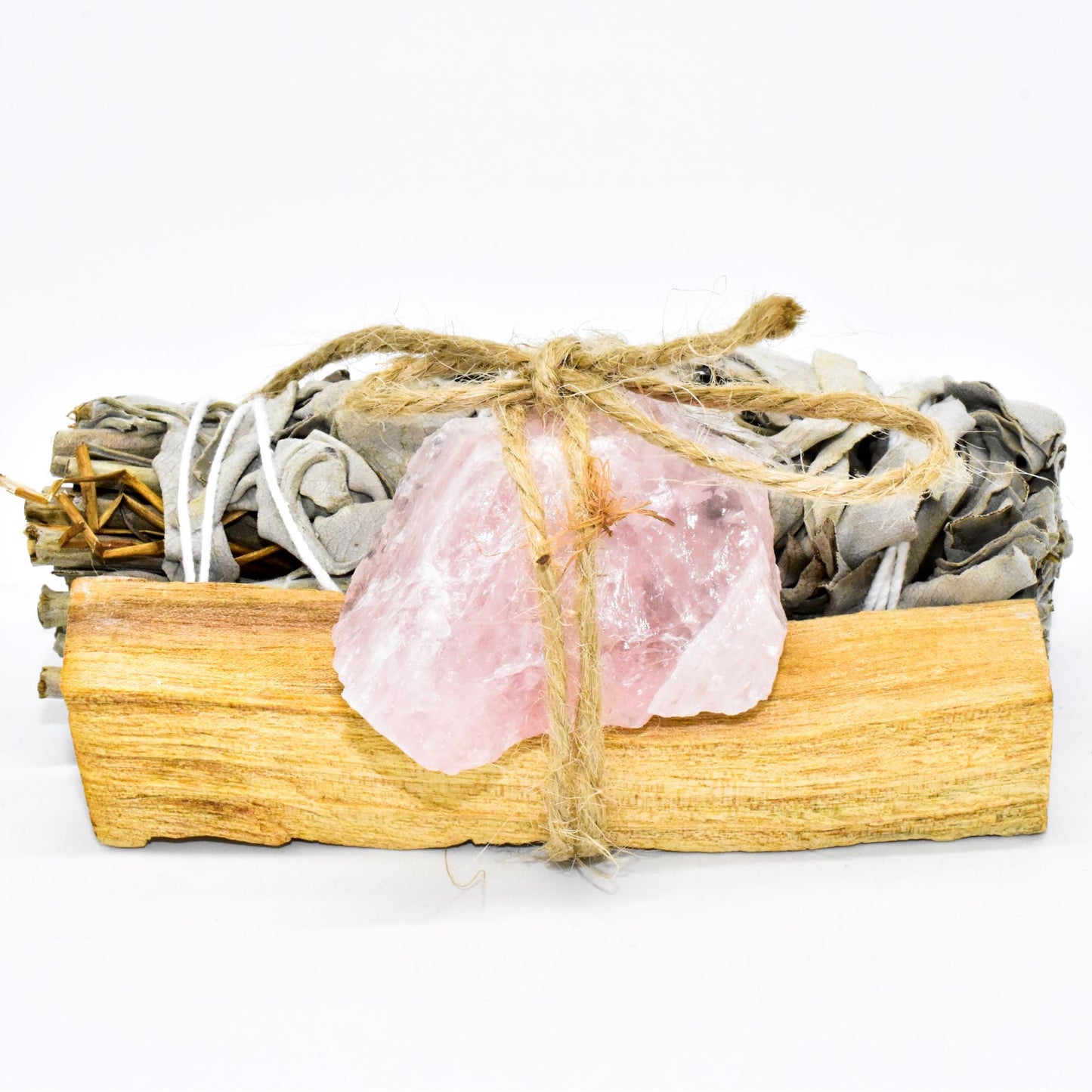 Sage bundle, rose quartz crystal, and wooden box on a white background