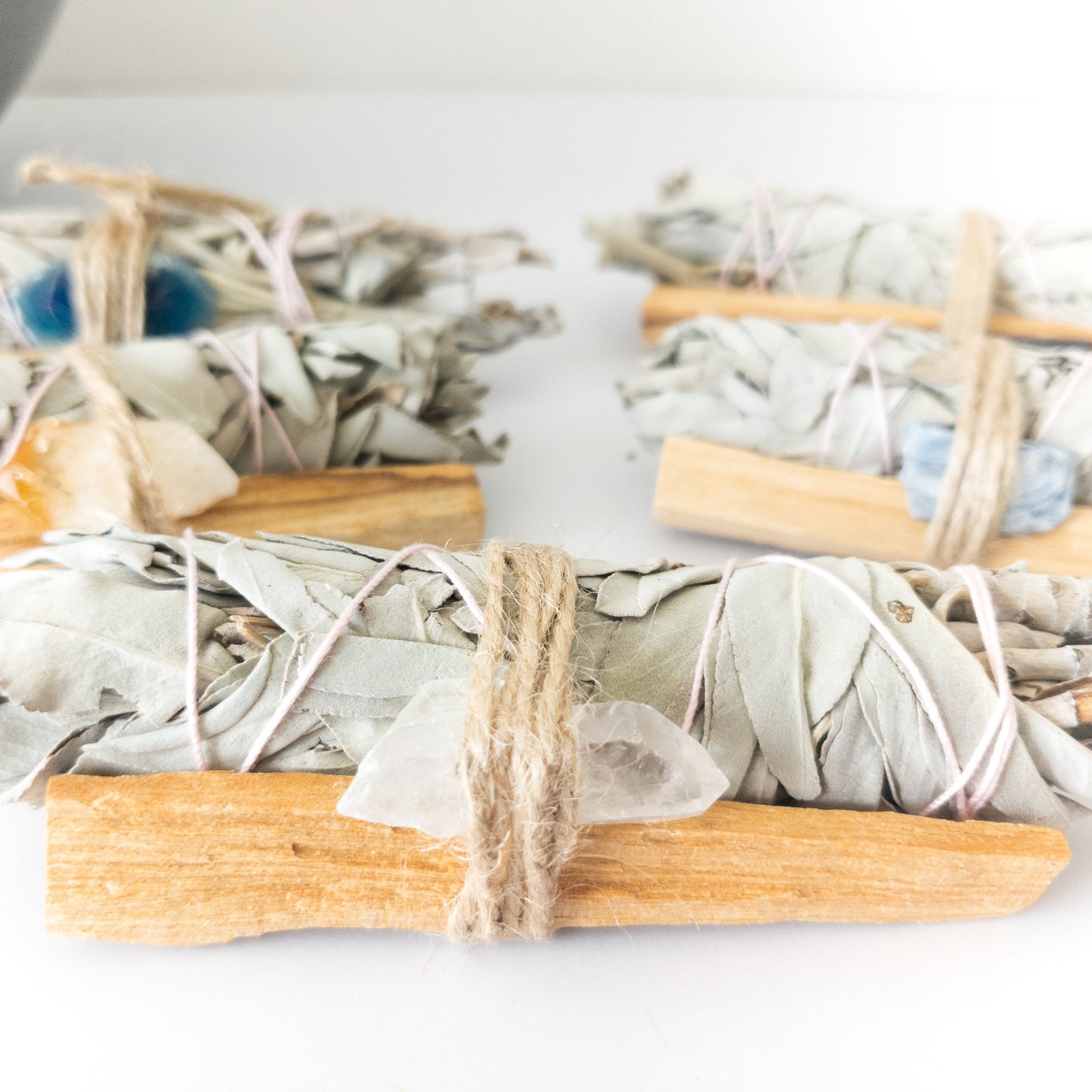 Three bundles of sage smudge sticks on a white surface