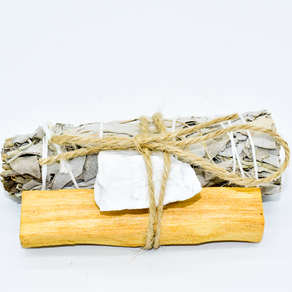 Sage bundle tied with twine, palo santo and a crystal on a white background