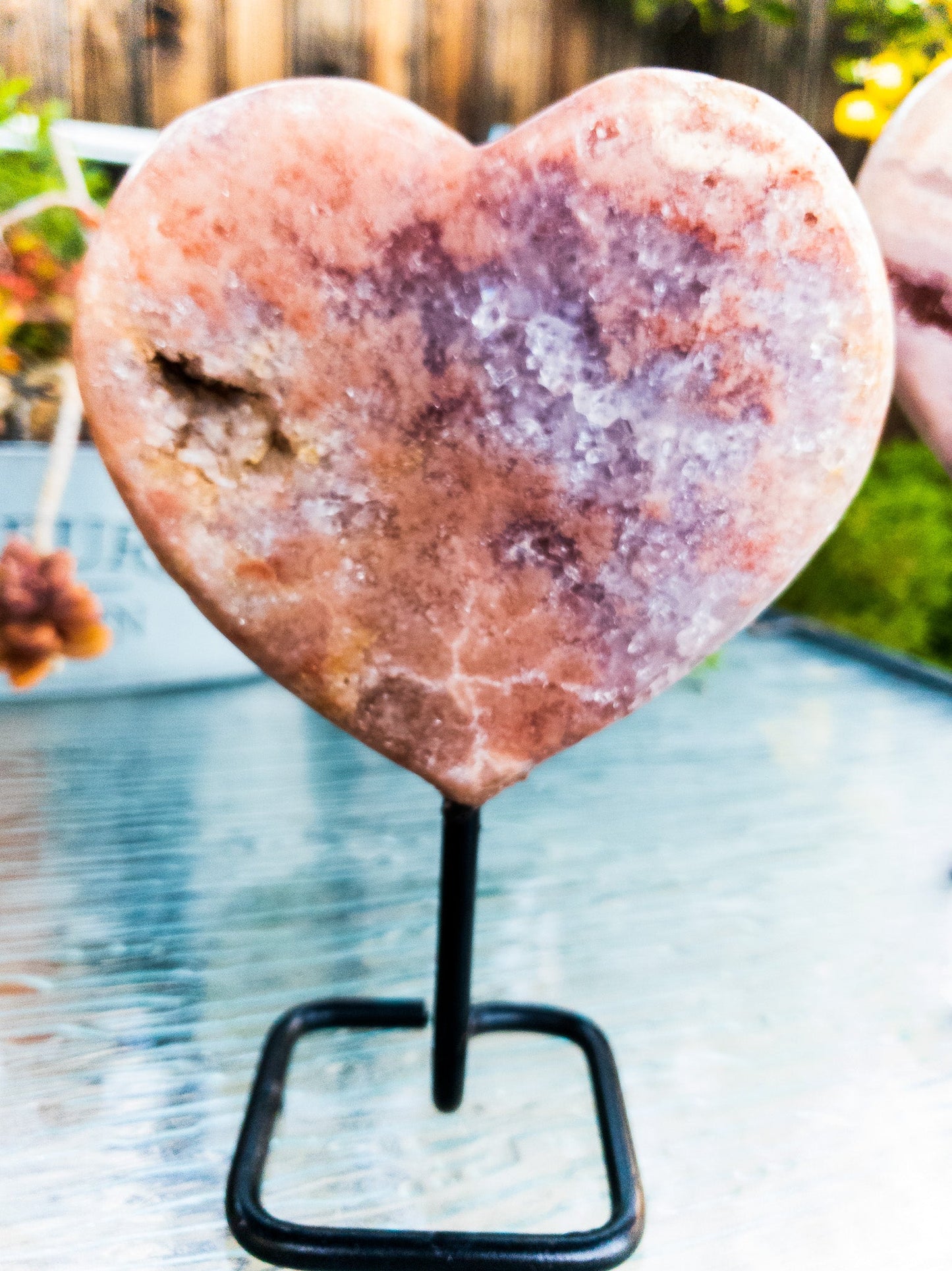Heart-shaped crystal on a stand with a blurred outdoor background