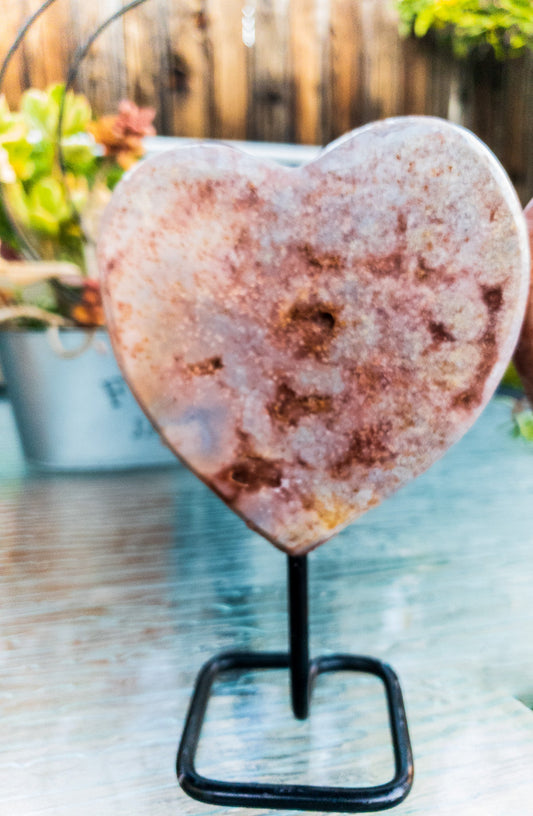 Heart-shaped crystal on a stand with a blurred outdoor background