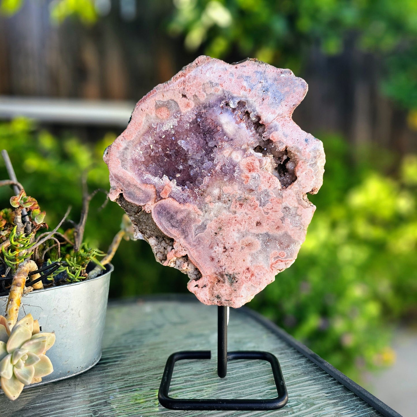 Pink crystal geode on a stand with greenery in the background