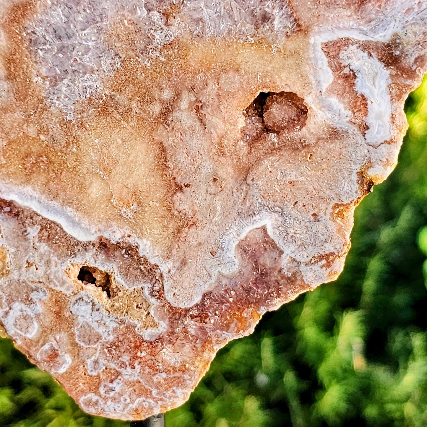 Close-up of a pink amethyst stone surface with a blurred green background
