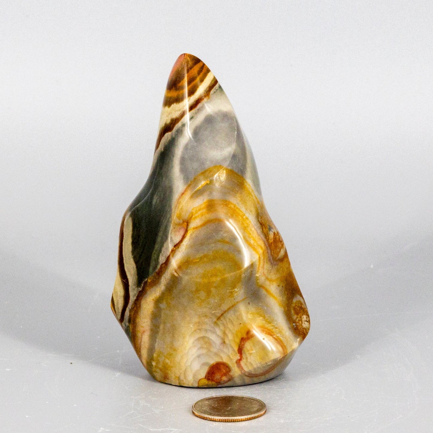 Polished polychrome jasper flame stone with yellow and brown patterns on a white background