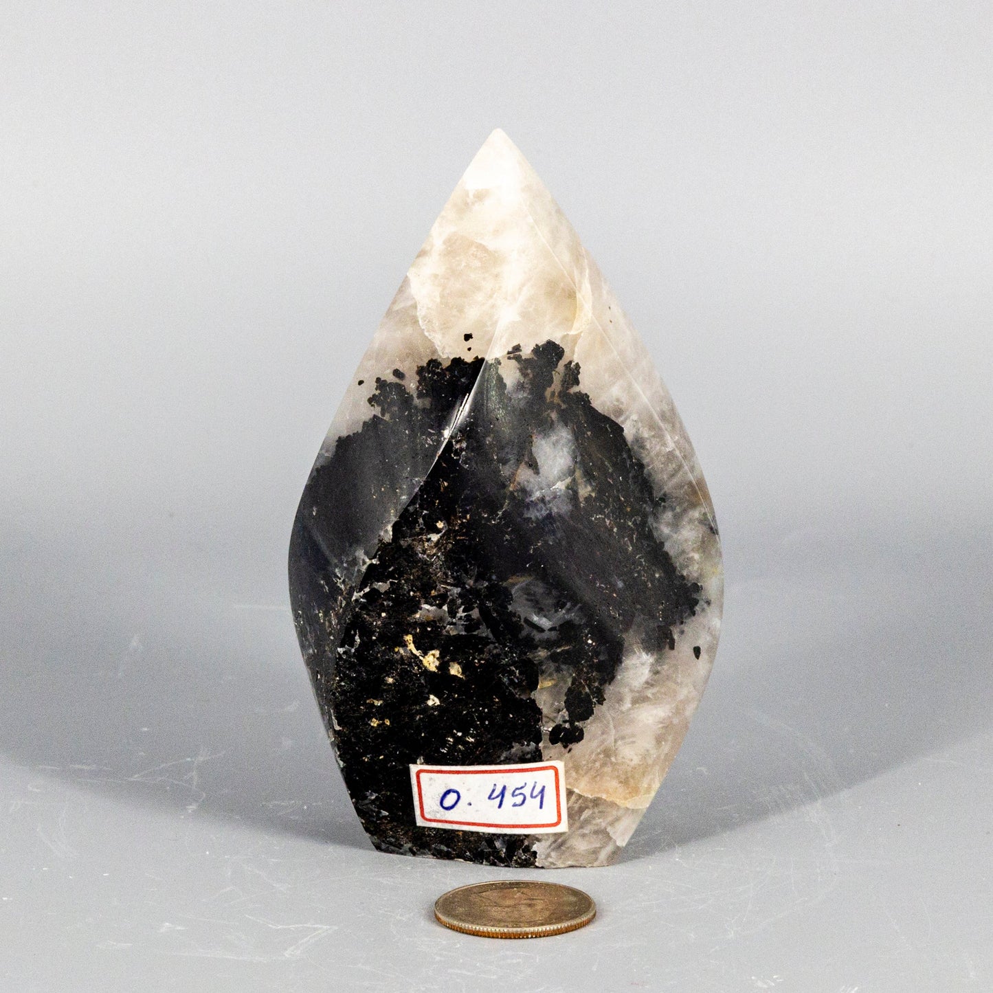 Teardrop-shaped crystal with black interior on a gray background