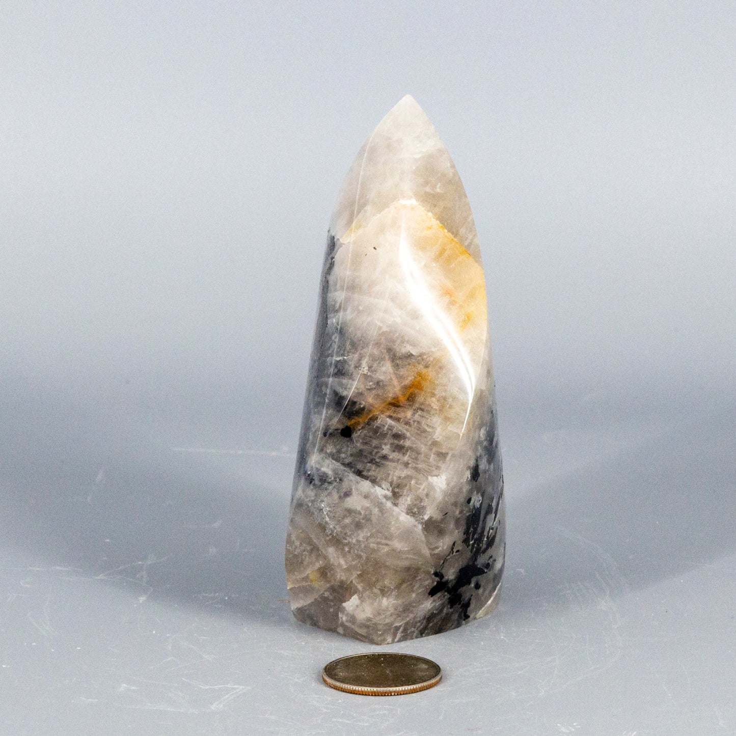 Tapered quartz with black tourmaline crystal with natural patterns on a gray background
