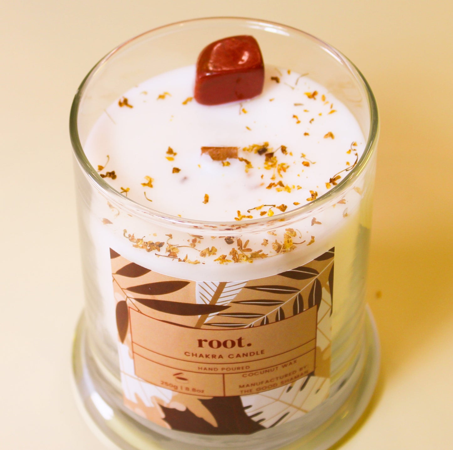 Root Chakra Candle in a glass jar with a decorative label on a beige background