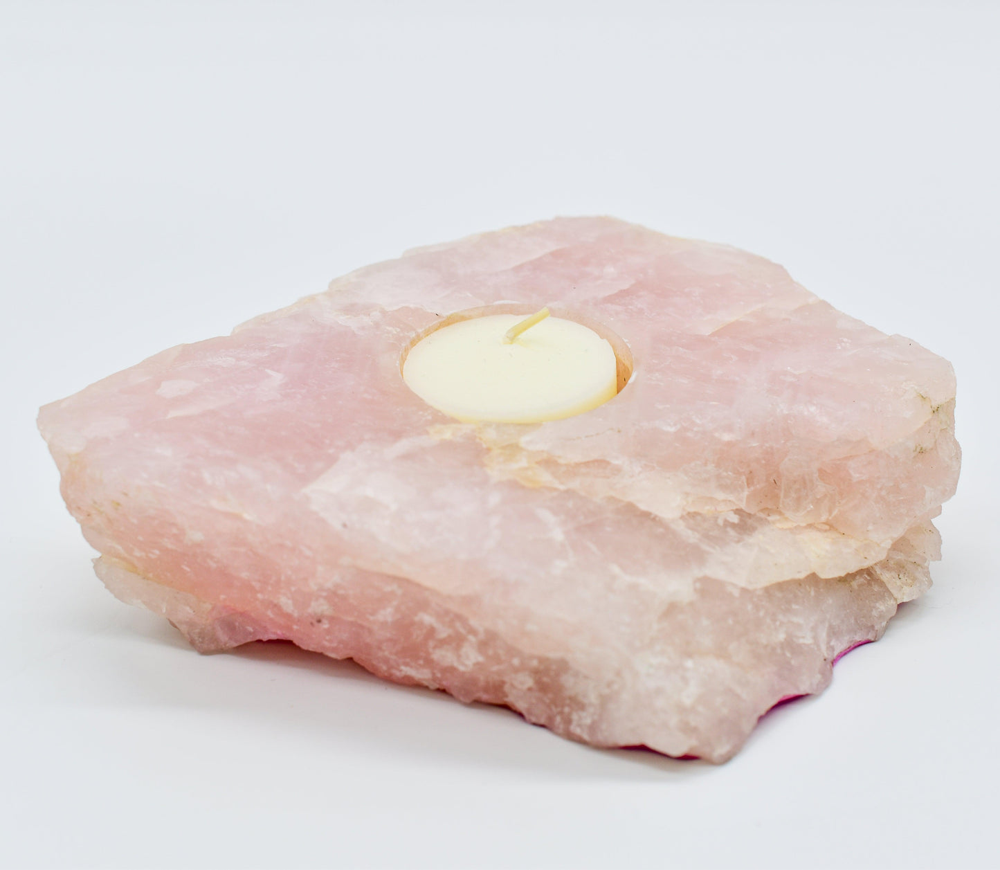 Rose quartz candle holder with a small amount of fat on a white background