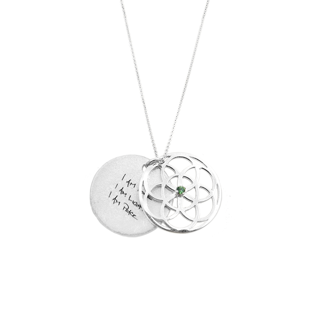 Silver necklace with seed of life pendant and engraved message on a white background