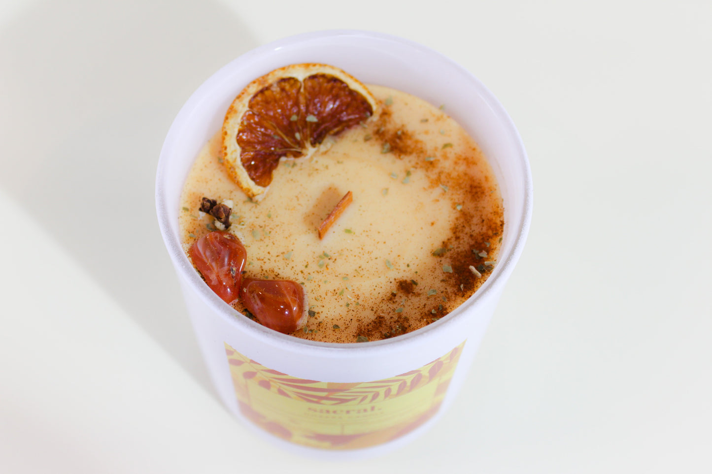 Sacral chakra candle with fruit pieces on a white background