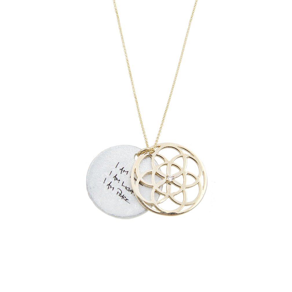 Necklace with a gold circular seed of life pendant and a white disc with text on a white background
