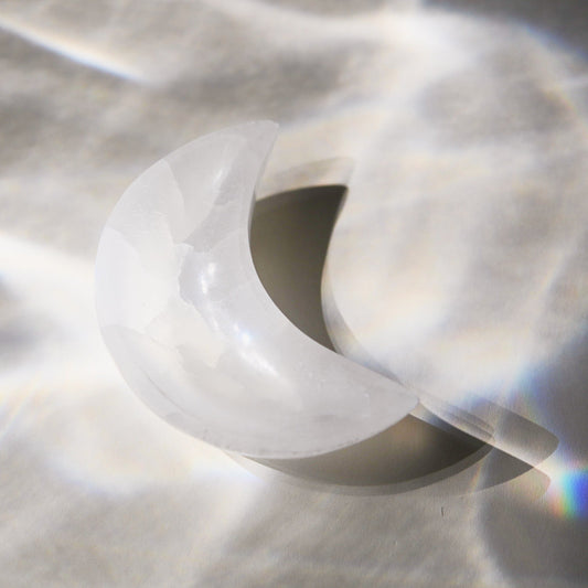 Selenite moon bowl on a textured gray background
