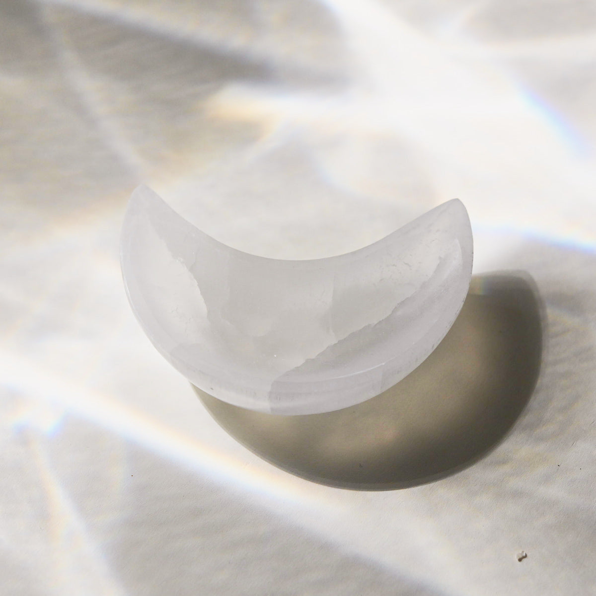 Selenite crescent moon-shaped bowl on a reflective surface