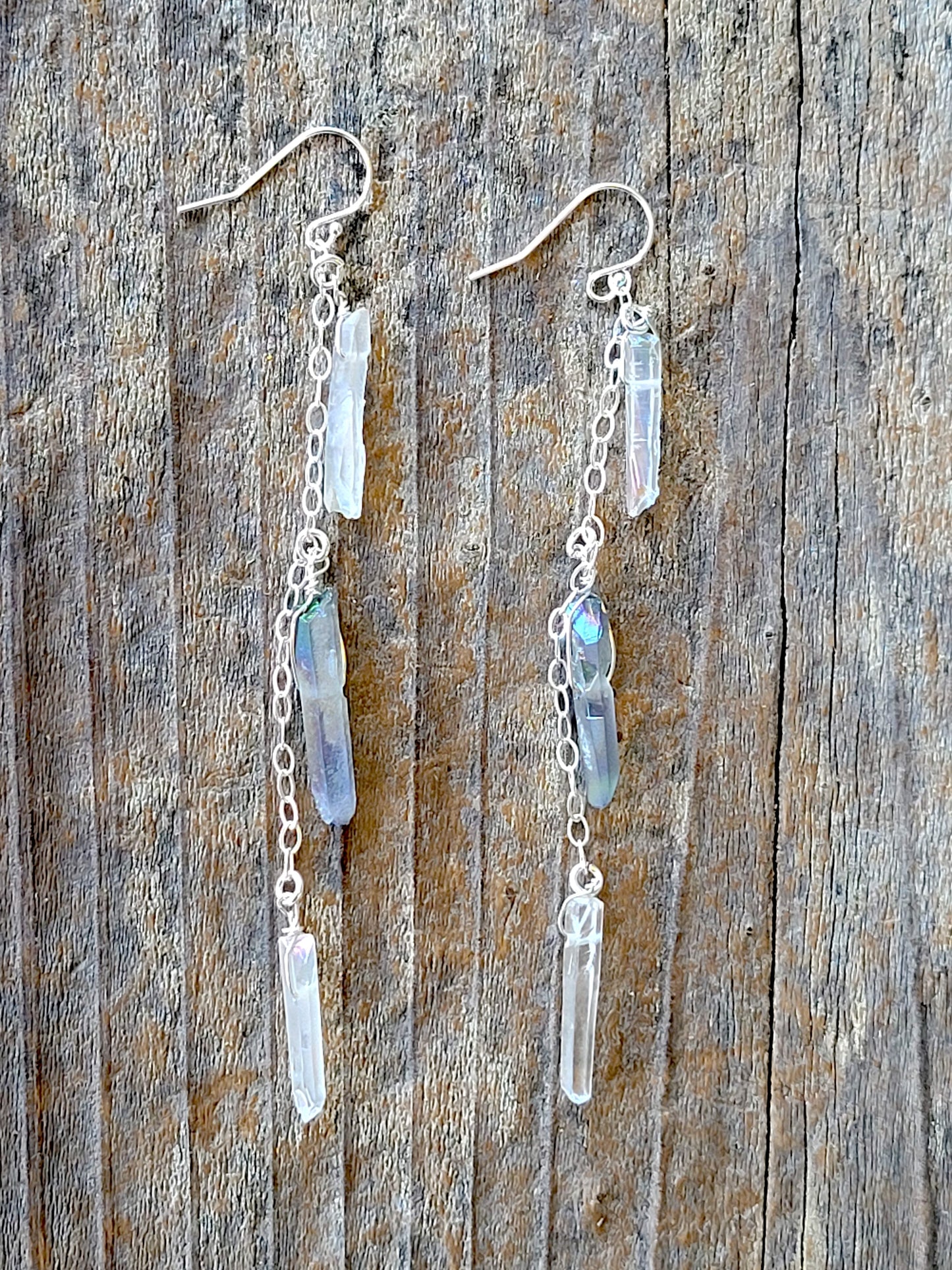 Silver chain earrings with crystal quartz on a wooden surface