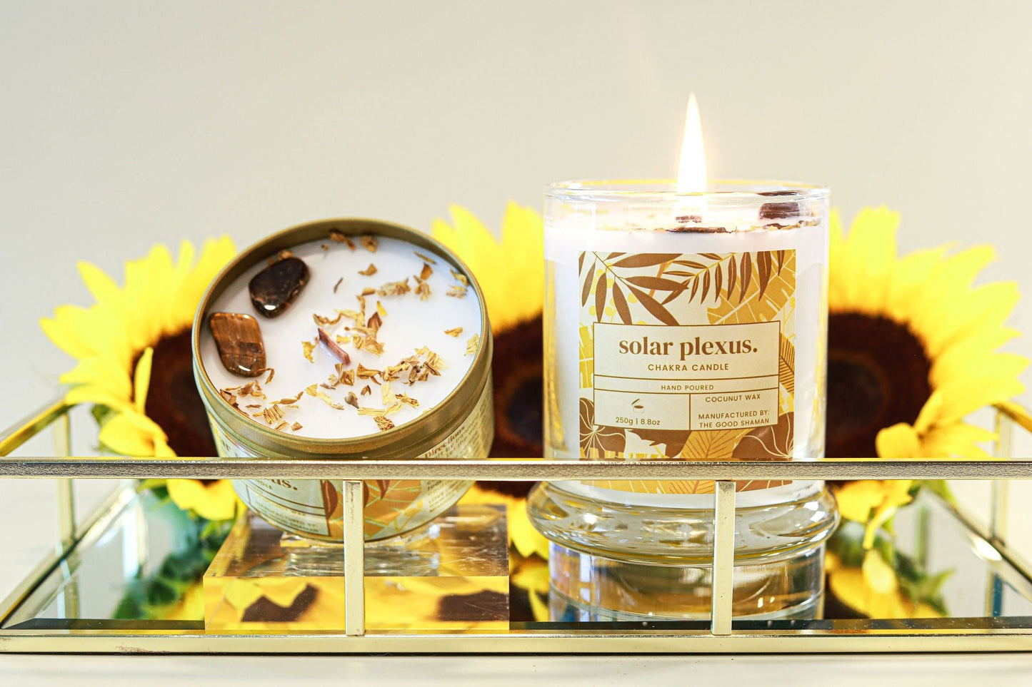 Candle labeled 'solar plexus' with decorative elements on a reflective surface.