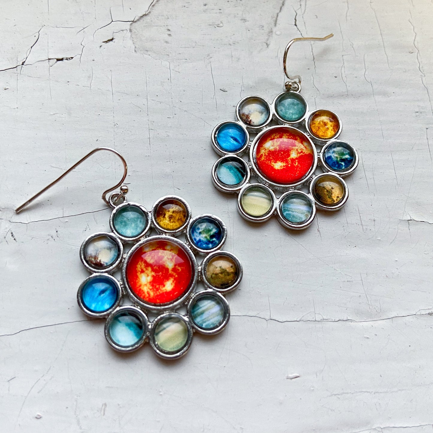 Colorful celestial-themed earrings on a textured white surface