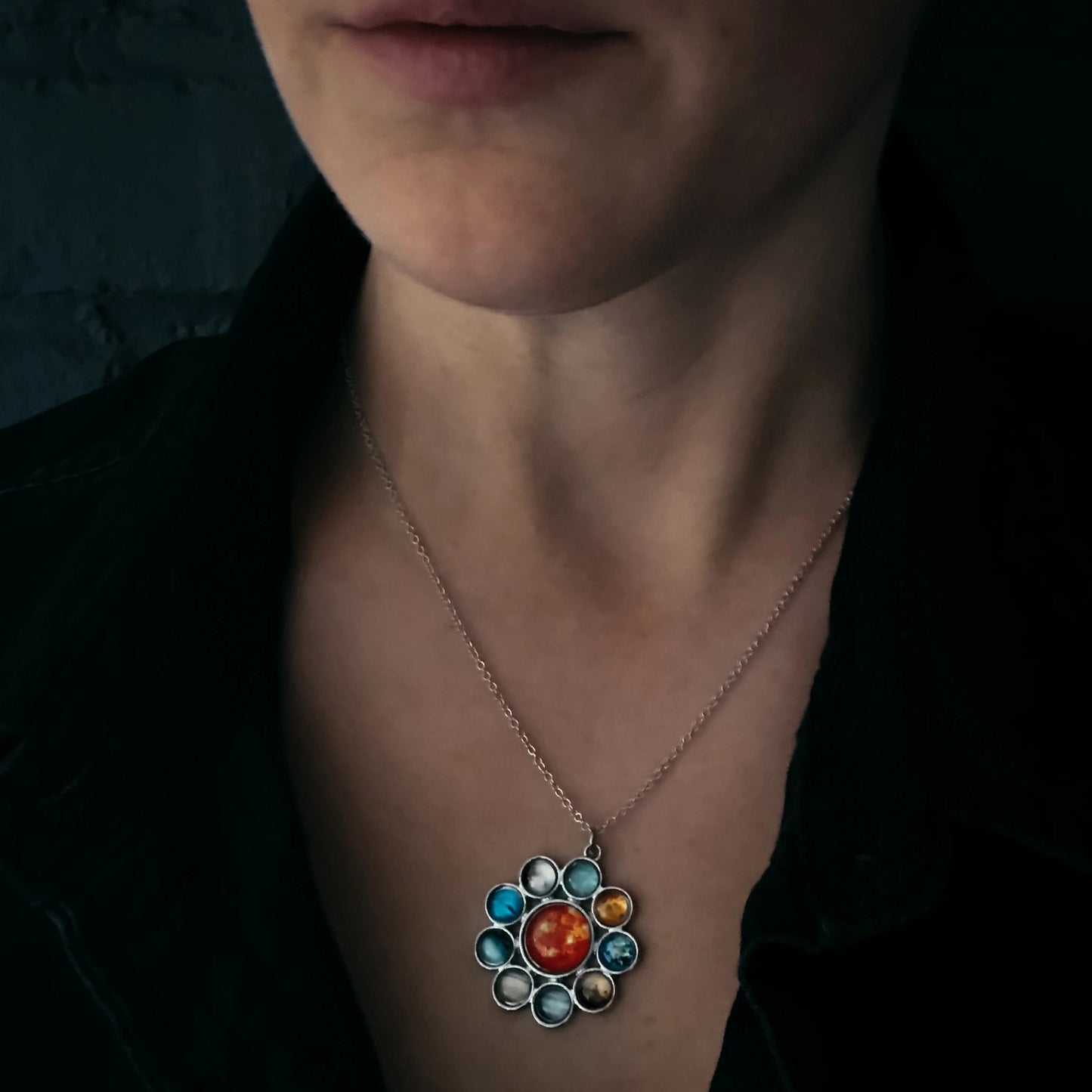 Necklace with a colorful pendant worn by a woman against a dark background