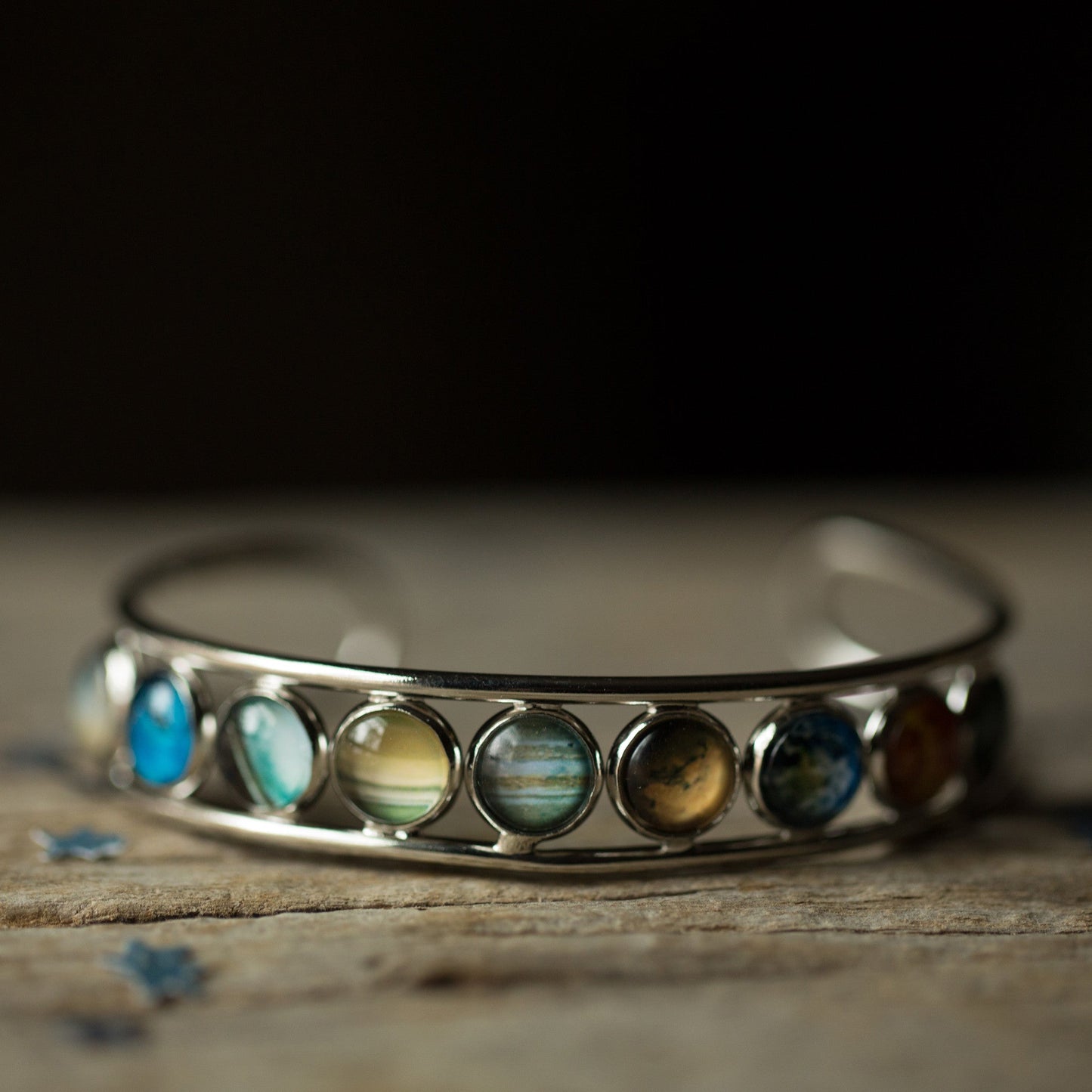 Silver bracelet with colorful stones on a wooden surface