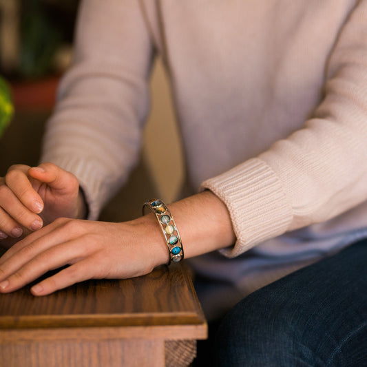 Person wearing a bracelet with colorful stones on a wooden surface