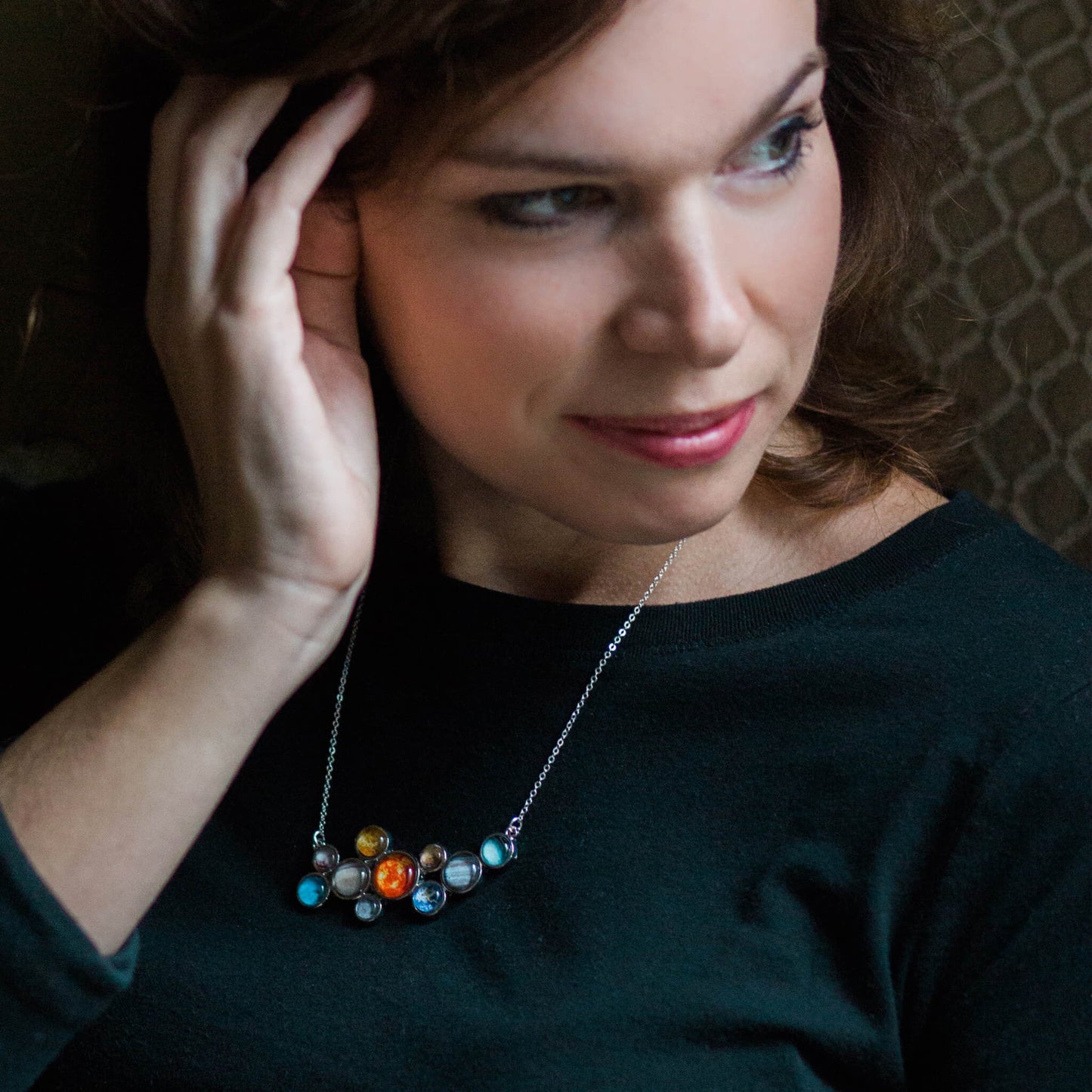 Woman wearing a black top and colorful necklace indoors