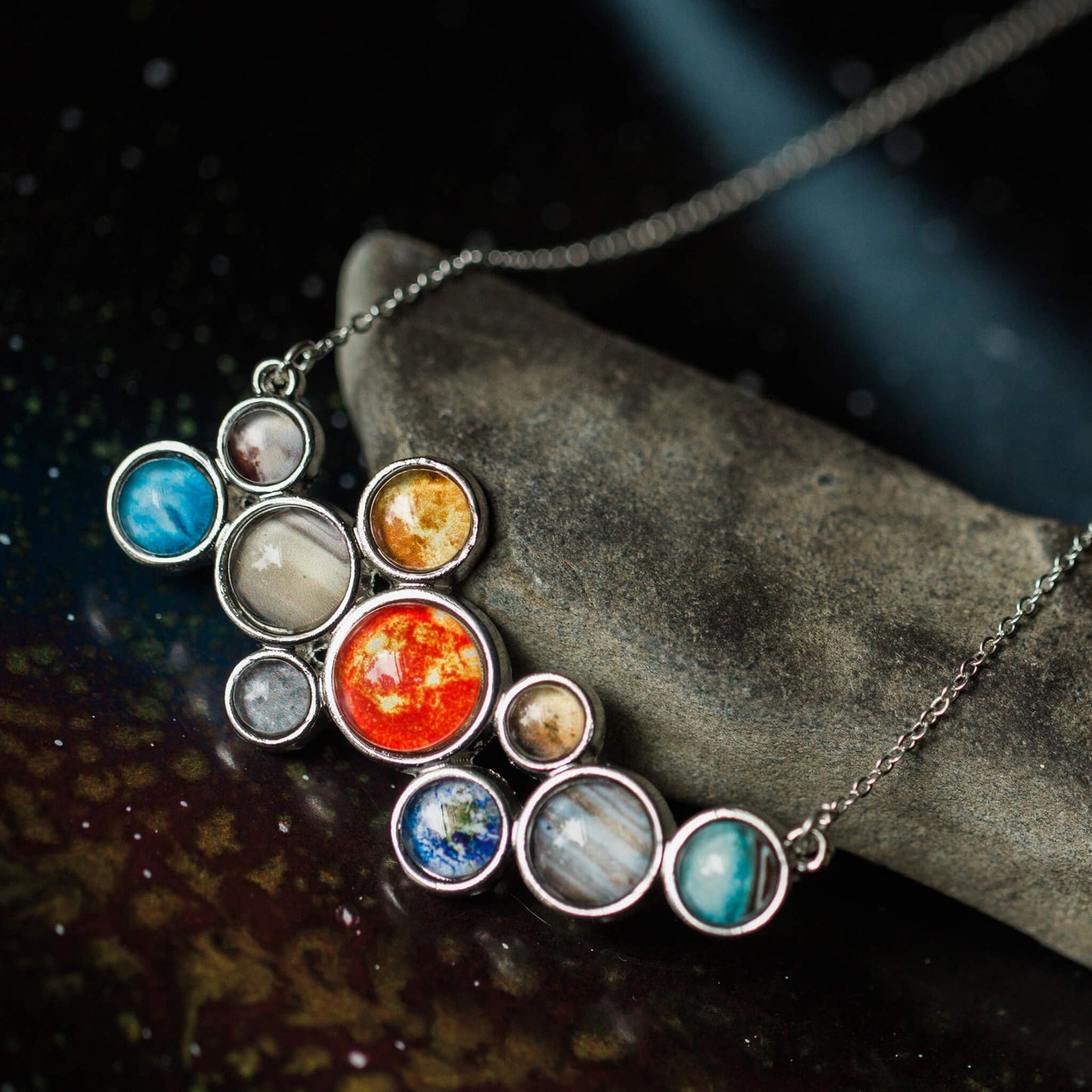 Necklace with planet-shaped pendants on a dark surface