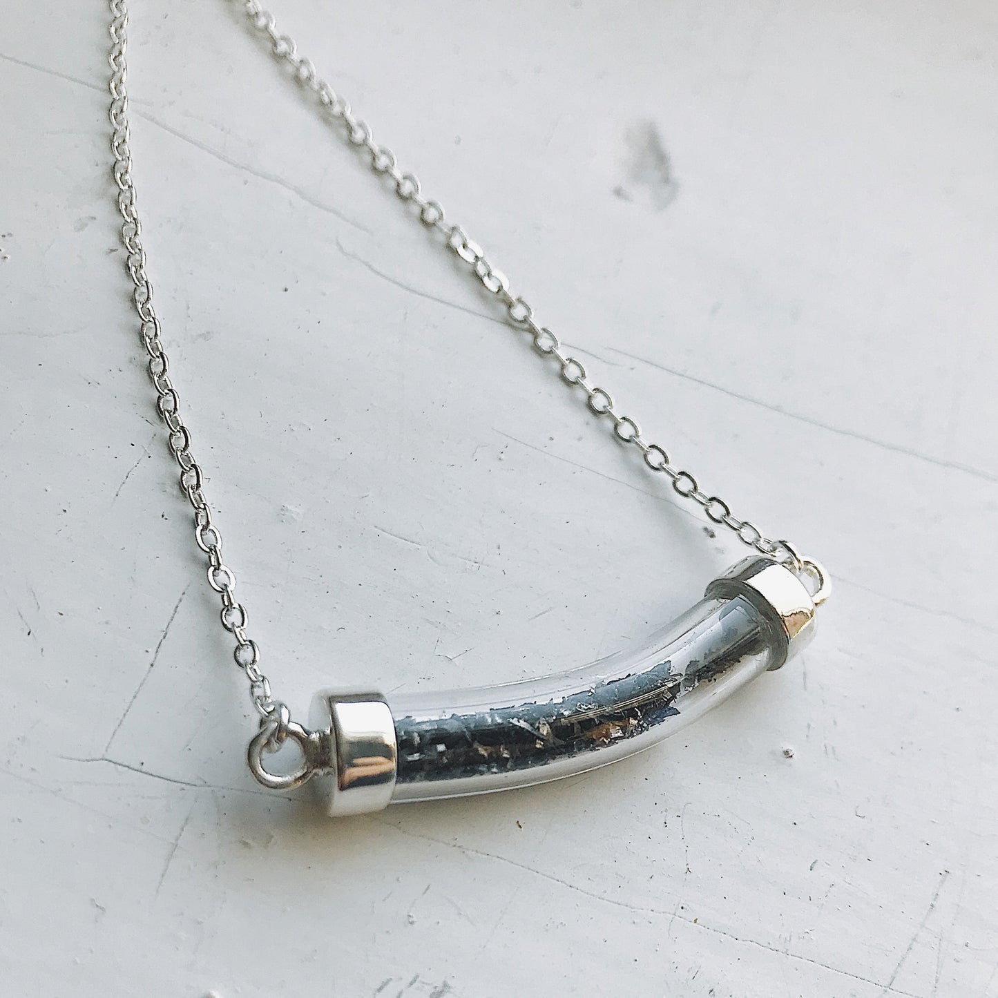 Necklace with a cylindrical pendant on a light gray background