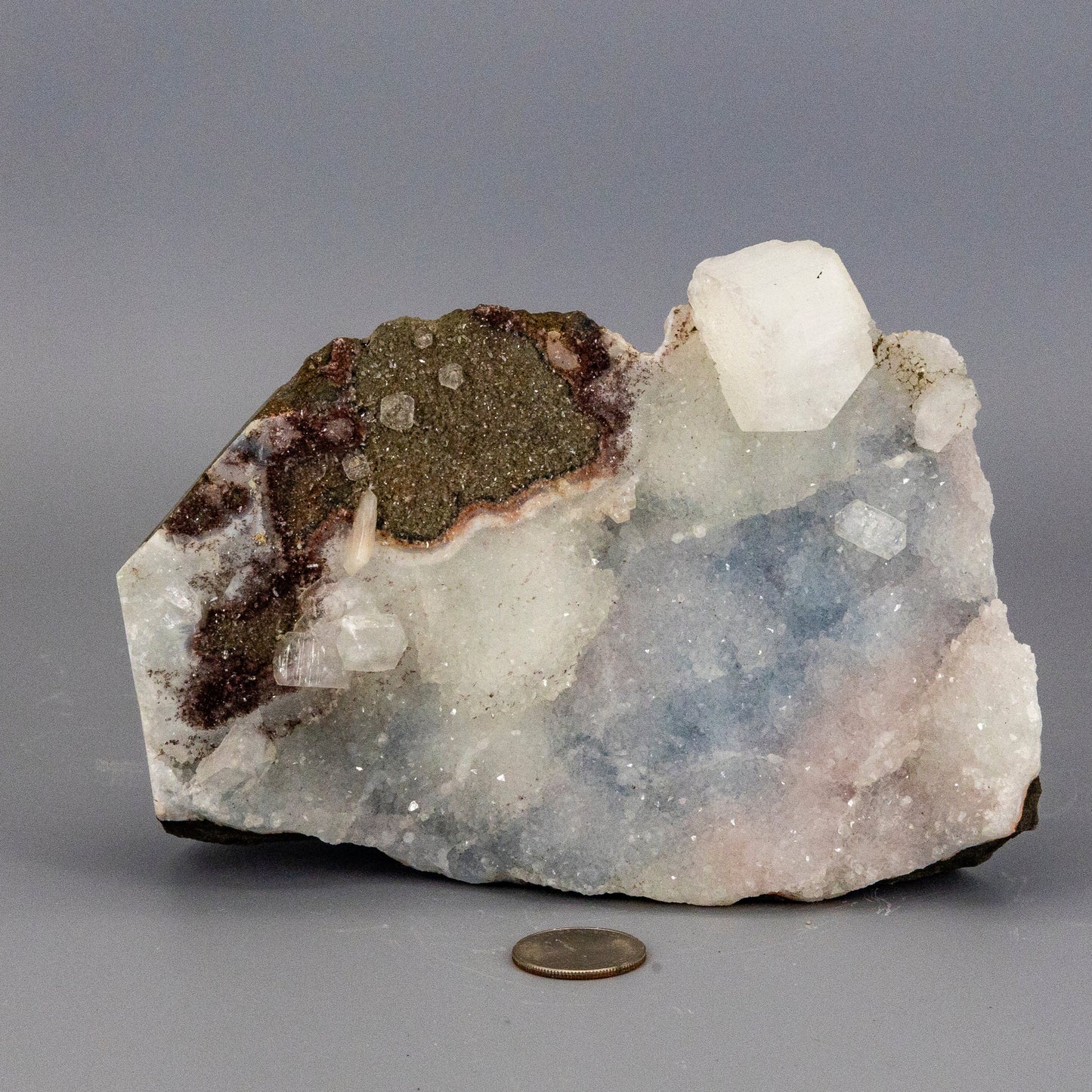 Chalcedony quartz cluster with a coin for scale on a gray background