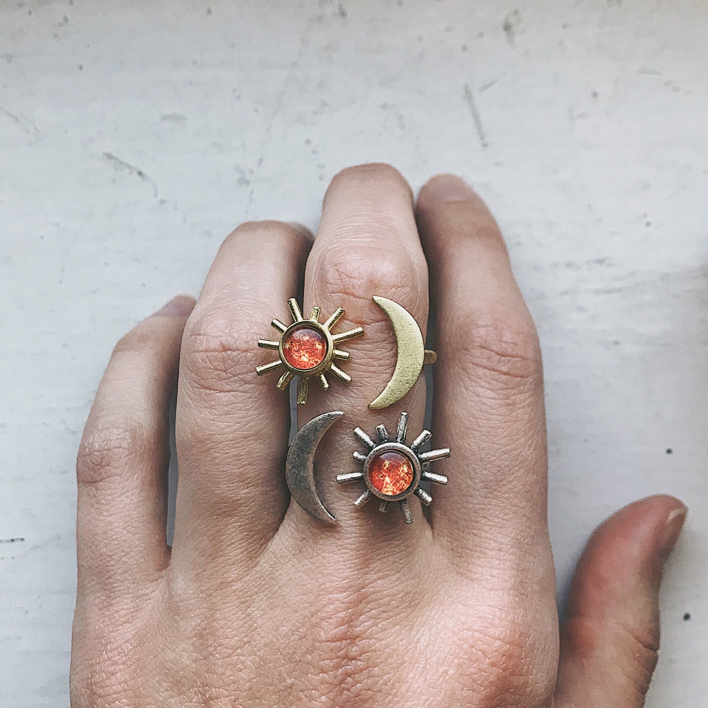 Hand wearing ring with sun and moon design on a light background