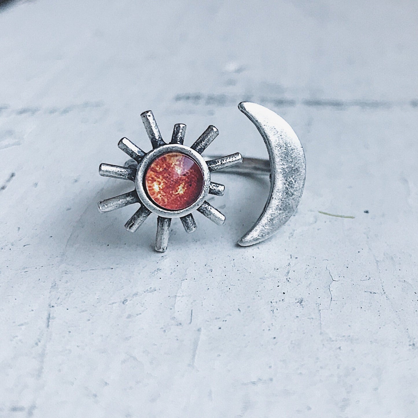 Silver sun and moon ring on a light gray surface