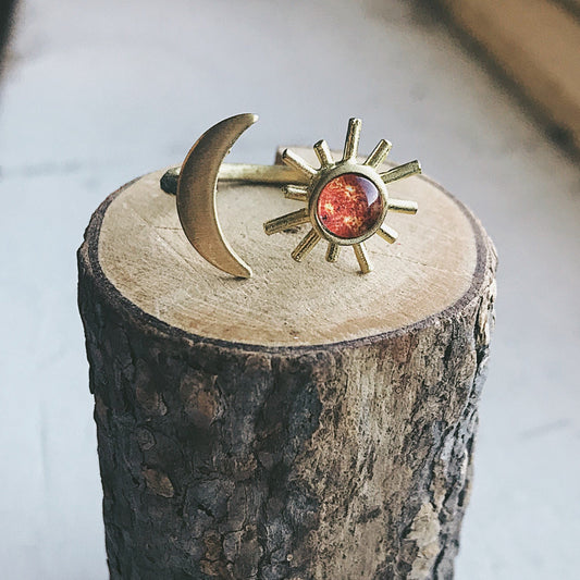 Gold ring with sun and moon design on a wooden block