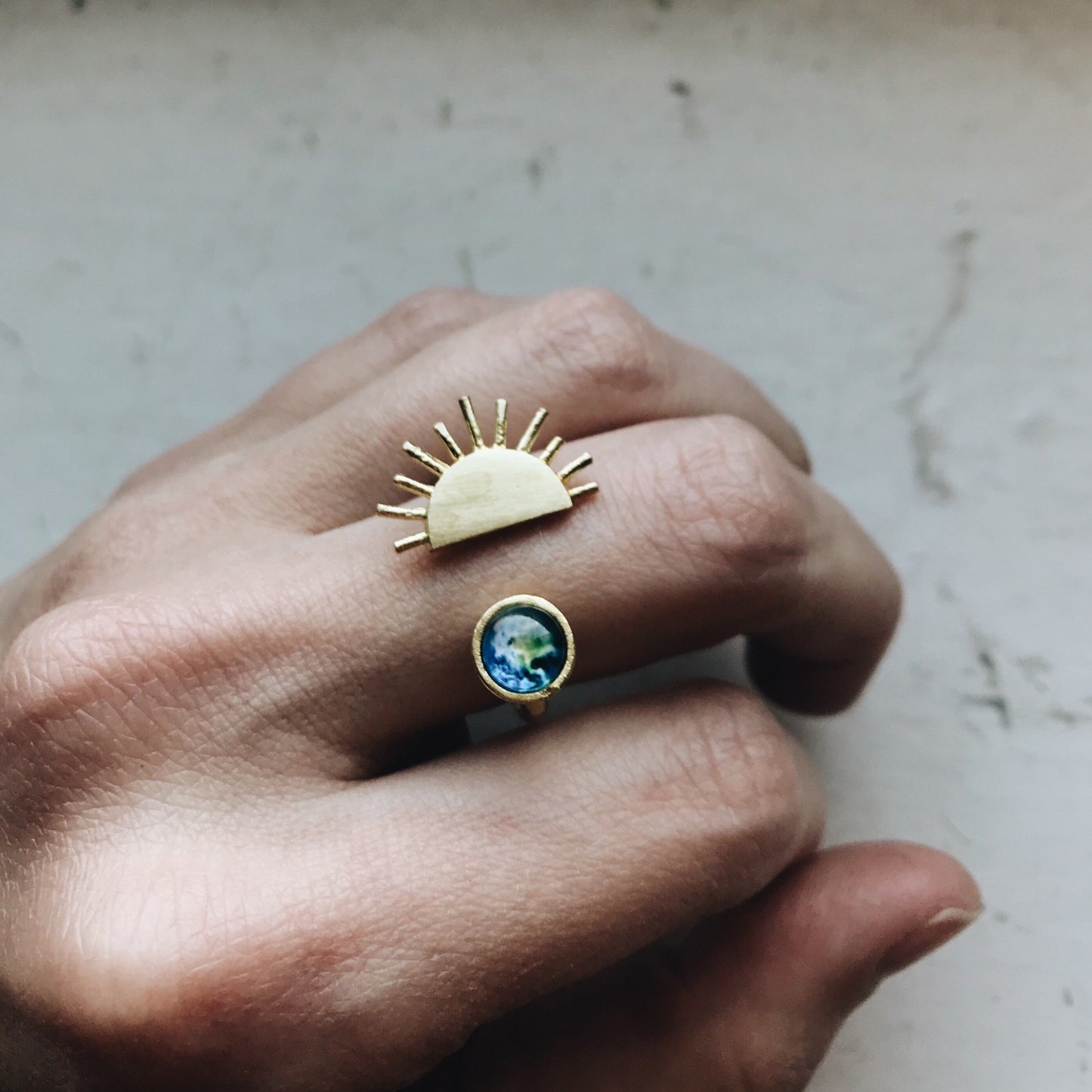 Hand wearing a ring with a sun design and with a gemstone.