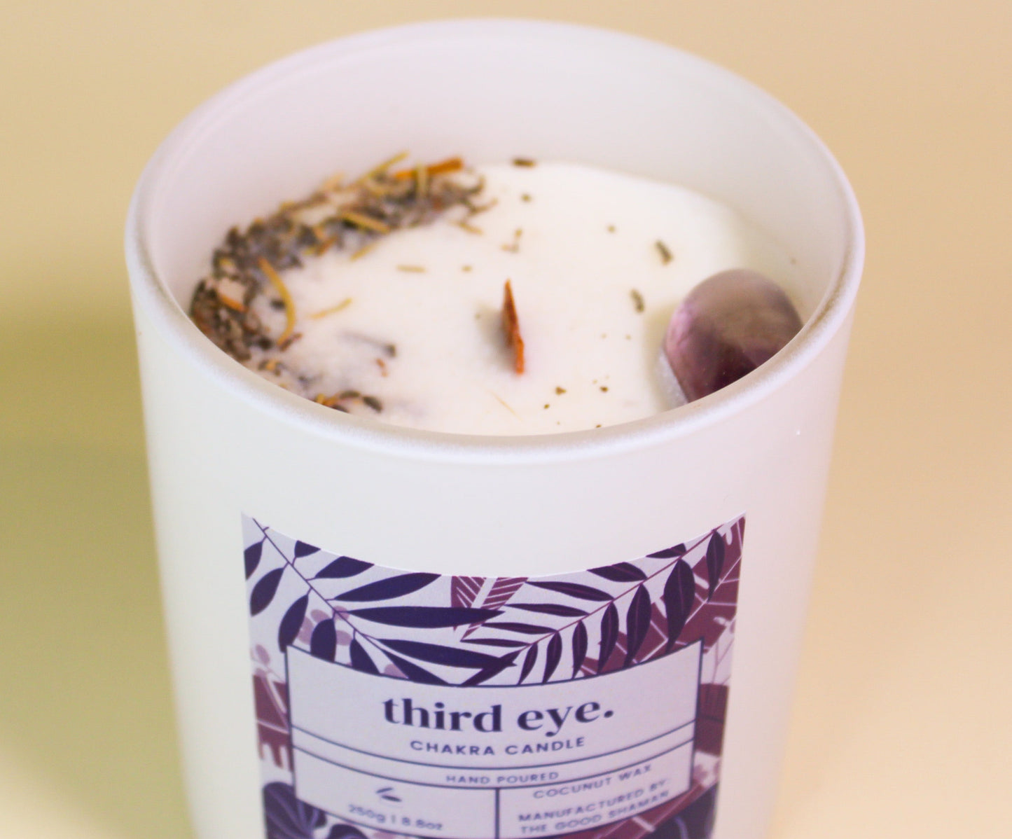 Candle in a white container with a 'third eye' label on a beige background