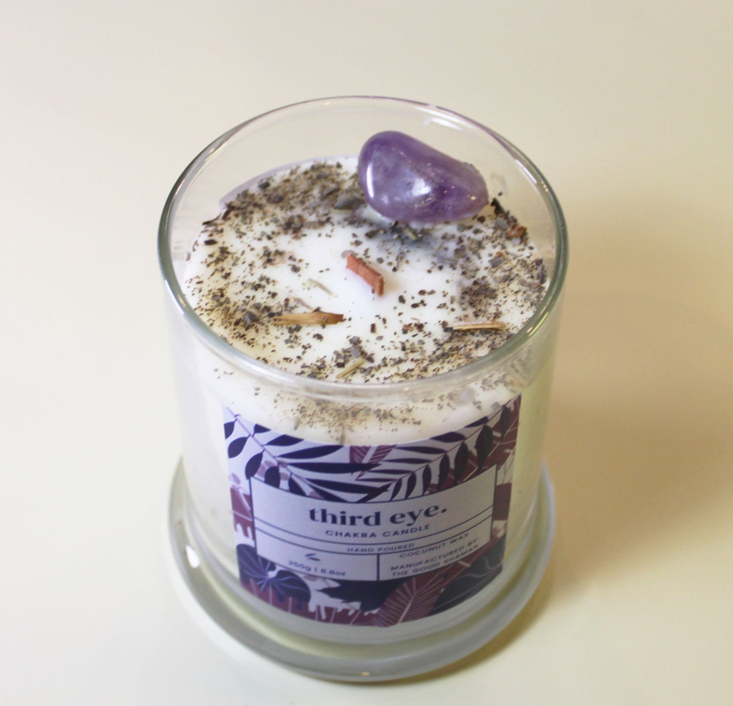 Glass candle with decorative elements and a label on a plain background