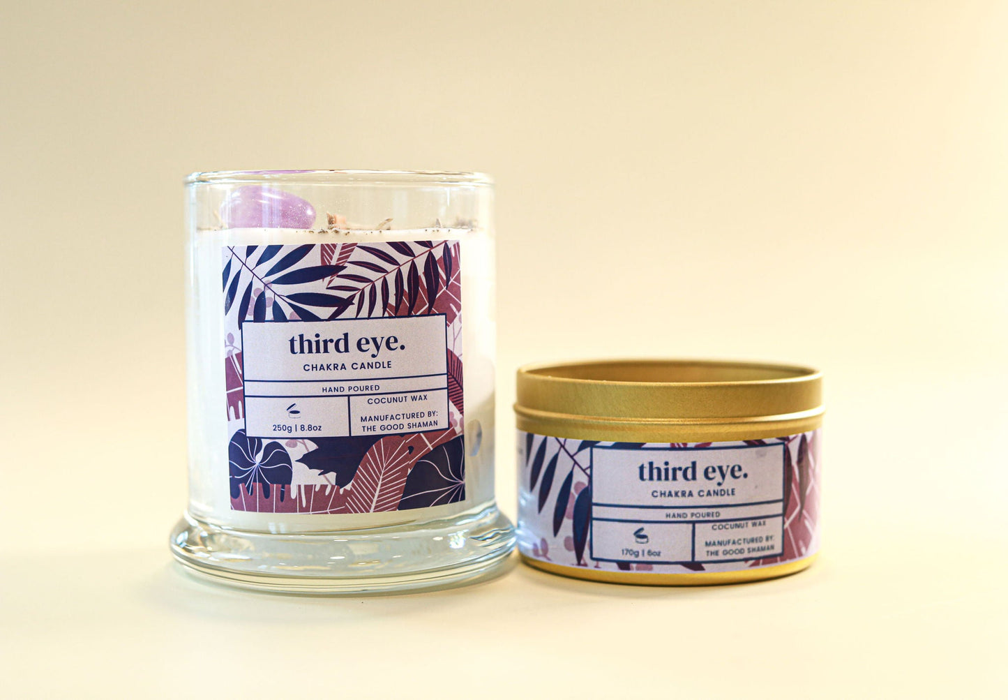 Two 'third eye.' candles, one in a glass jar and one in a tin, on a beige background.