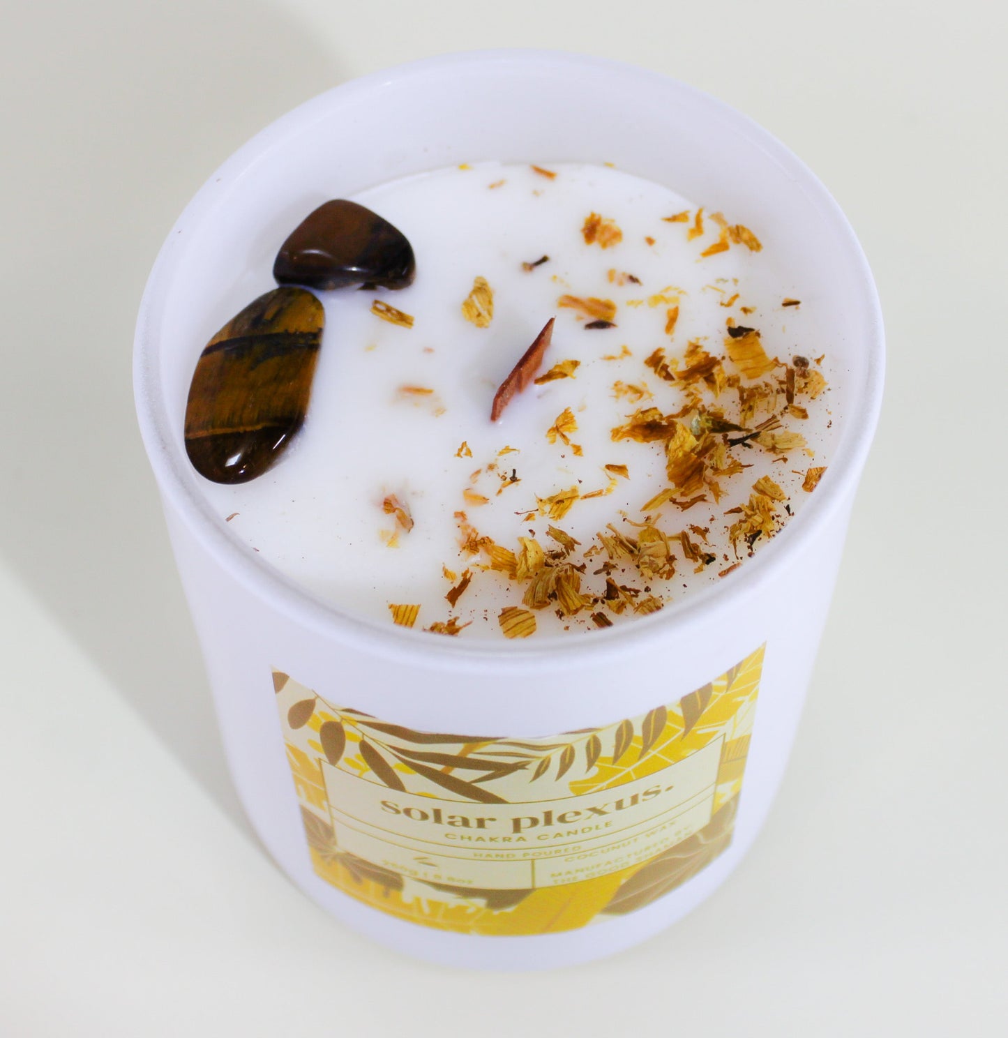 Throat chakra candle in a white container with decorative elements on a light background