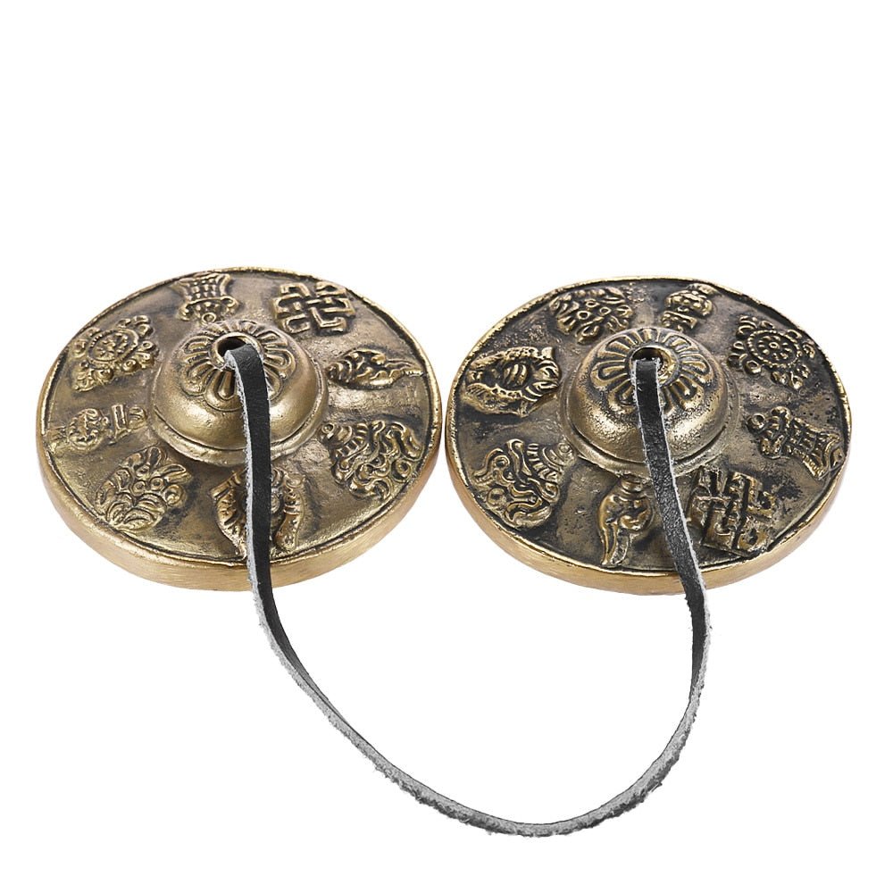 Pair of bronze hand chimes with intricate designs on a white background