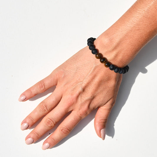 Hand wearing a black beaded bracelet on a white background