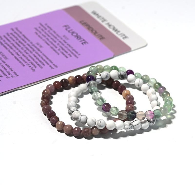 Set of multicolored beaded bracelets on a white surface with a purple card in the background.