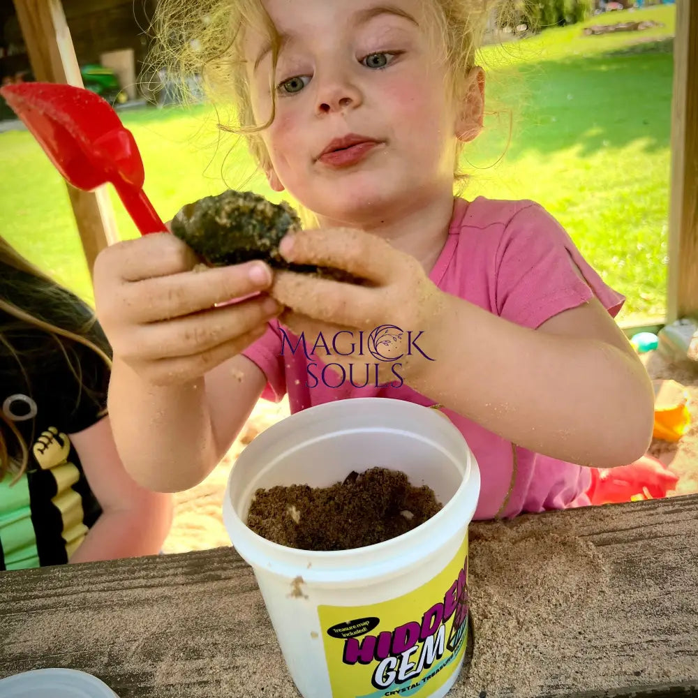 Child holding a crystal next to a container.