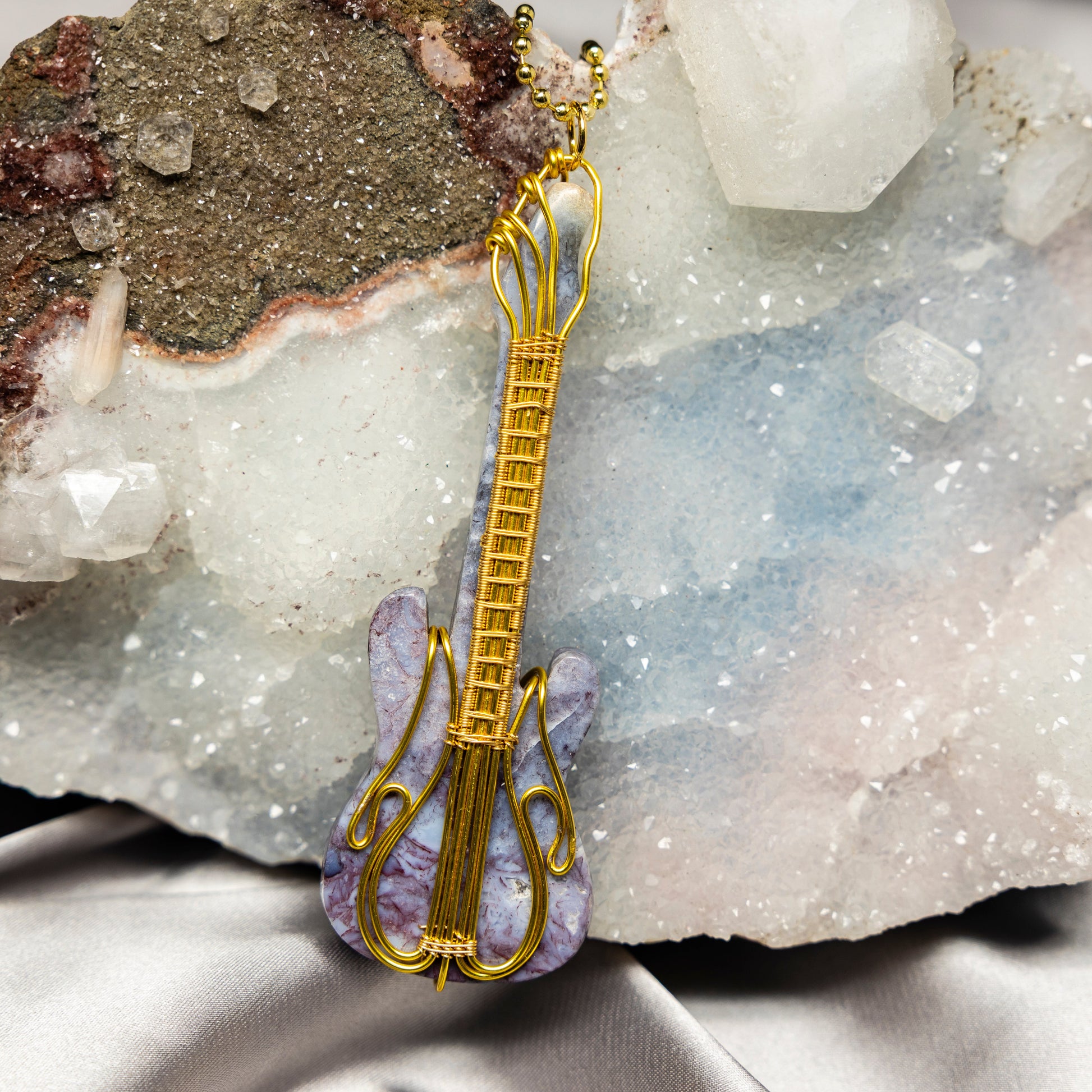 Gold guitar-shaped pendant with agate on a crystal background