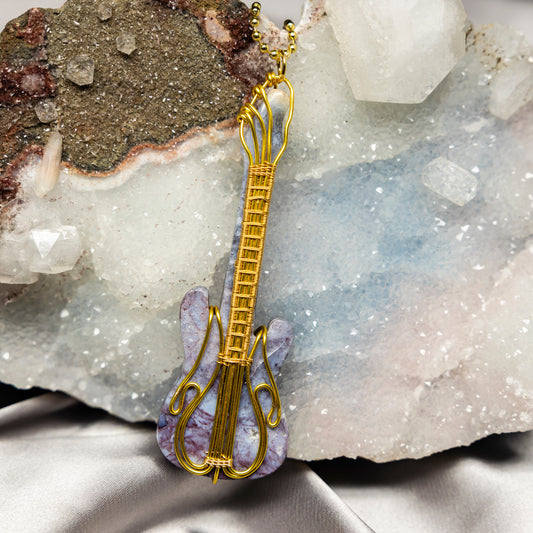 Gold guitar-shaped pendant with agate on a crystal background