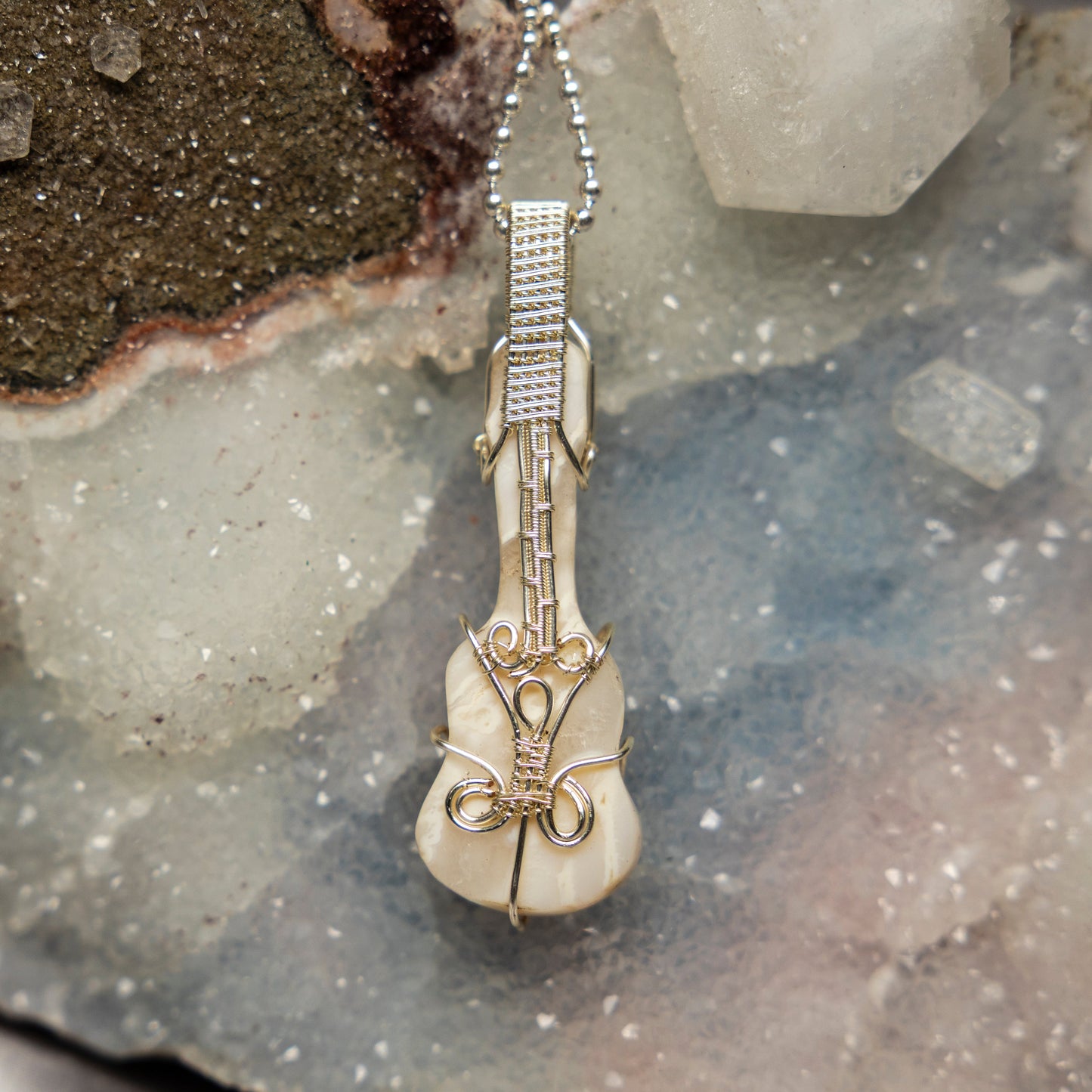 Violin-shaped agate pendant on a chain against a textured stone background