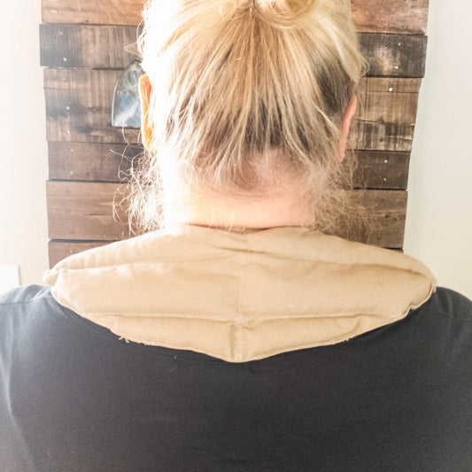 Person wearing a beige neck warmer with amethyst with a wooden wall background
