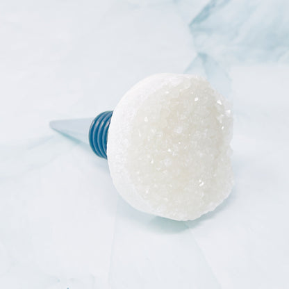 Close-up of a white crystal wine bottle stopper on a light blue background