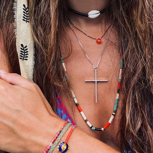 Close-up of a person wearing a cross necklace and colorful beaded necklaces with a headband.